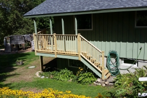 green building with wooden deck and steps