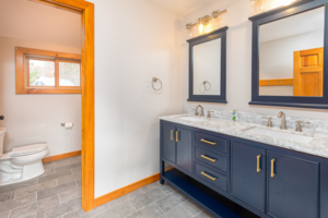blue cabinets in bathroom with marble counter and mirrors