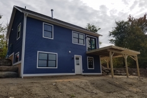dark blue home with wooden deck